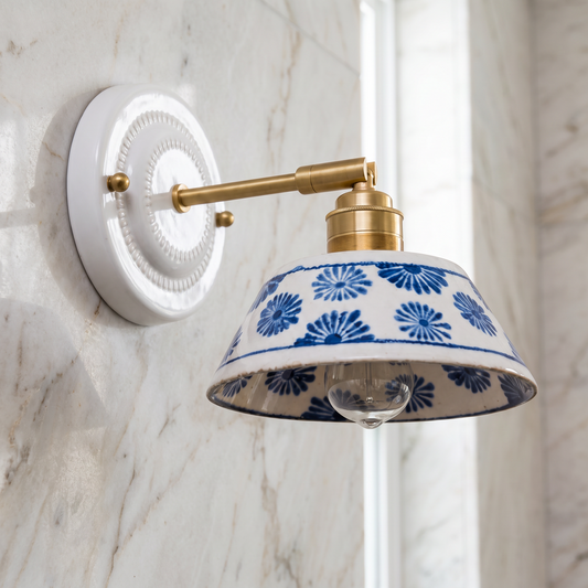 Close-up of the glazed ceramic shade, blue floral print and gold-tone brass arm in daylight