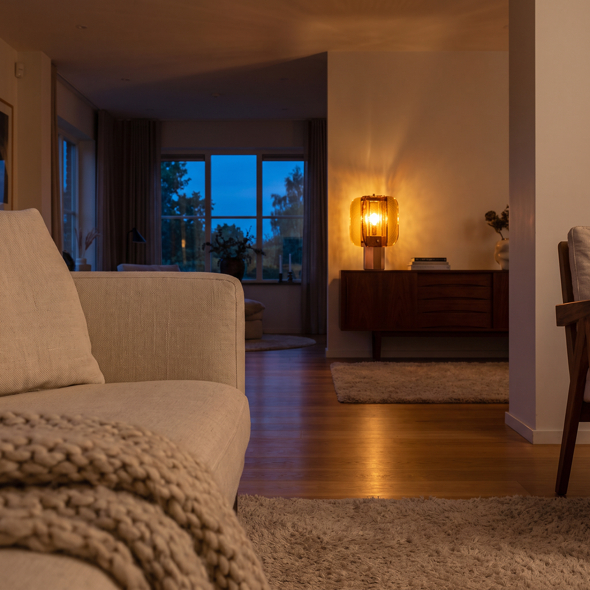 Amber glass table lamp glowing across a living room in the evening